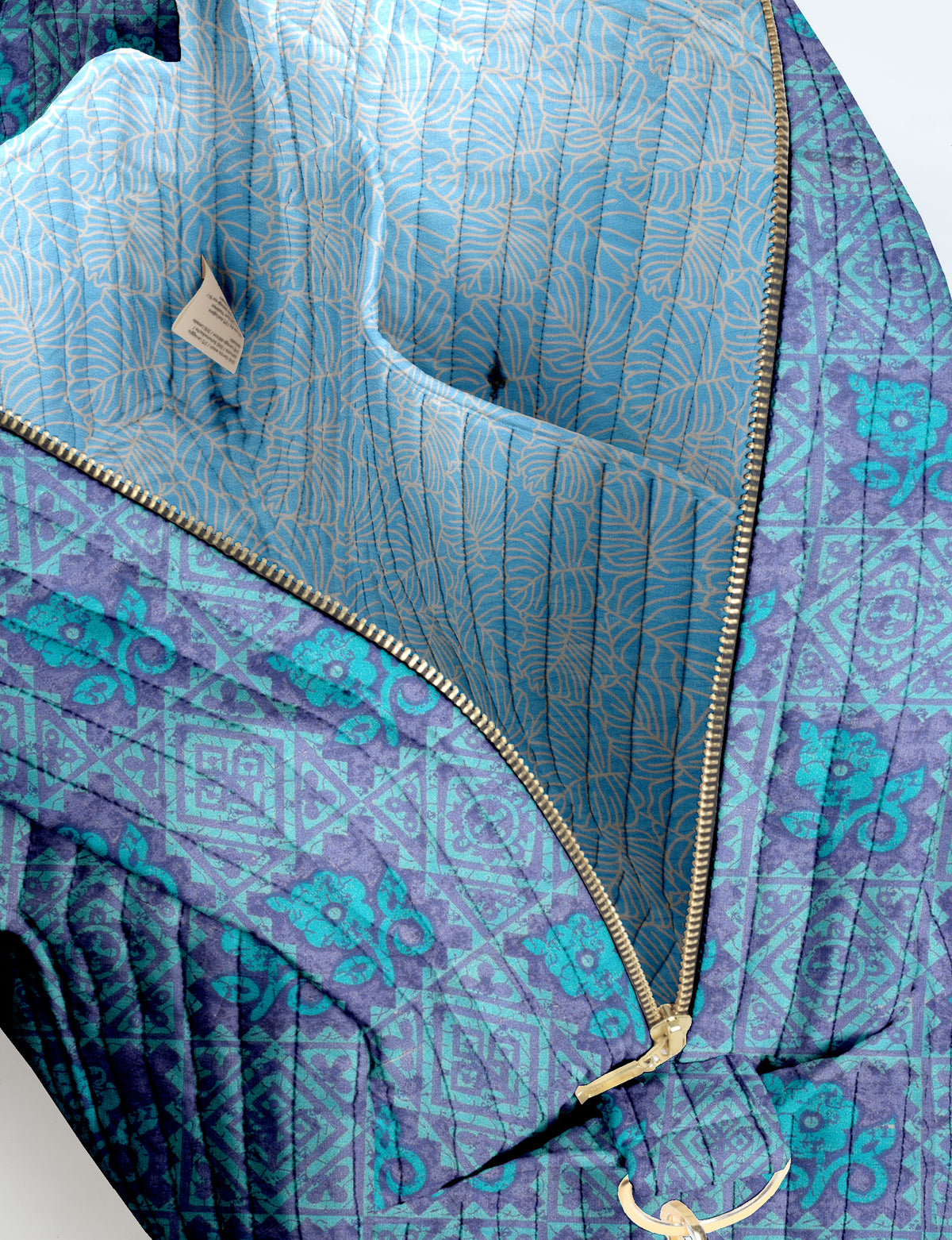 Brown quilted duffle bag with paisley pattern, front zip pocket, dual handles, and label reading "I was a sari"