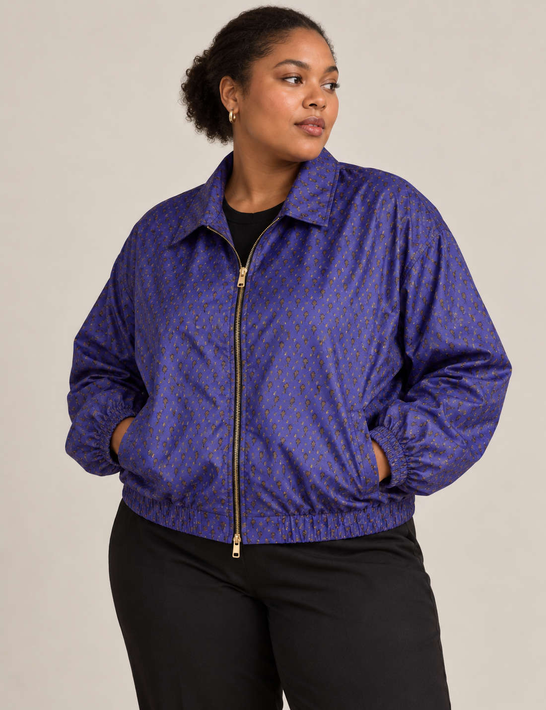 Woman wearing a yellow floral bomber jacket with front zipper, elastic cuffs, and side pockets, shown from front view