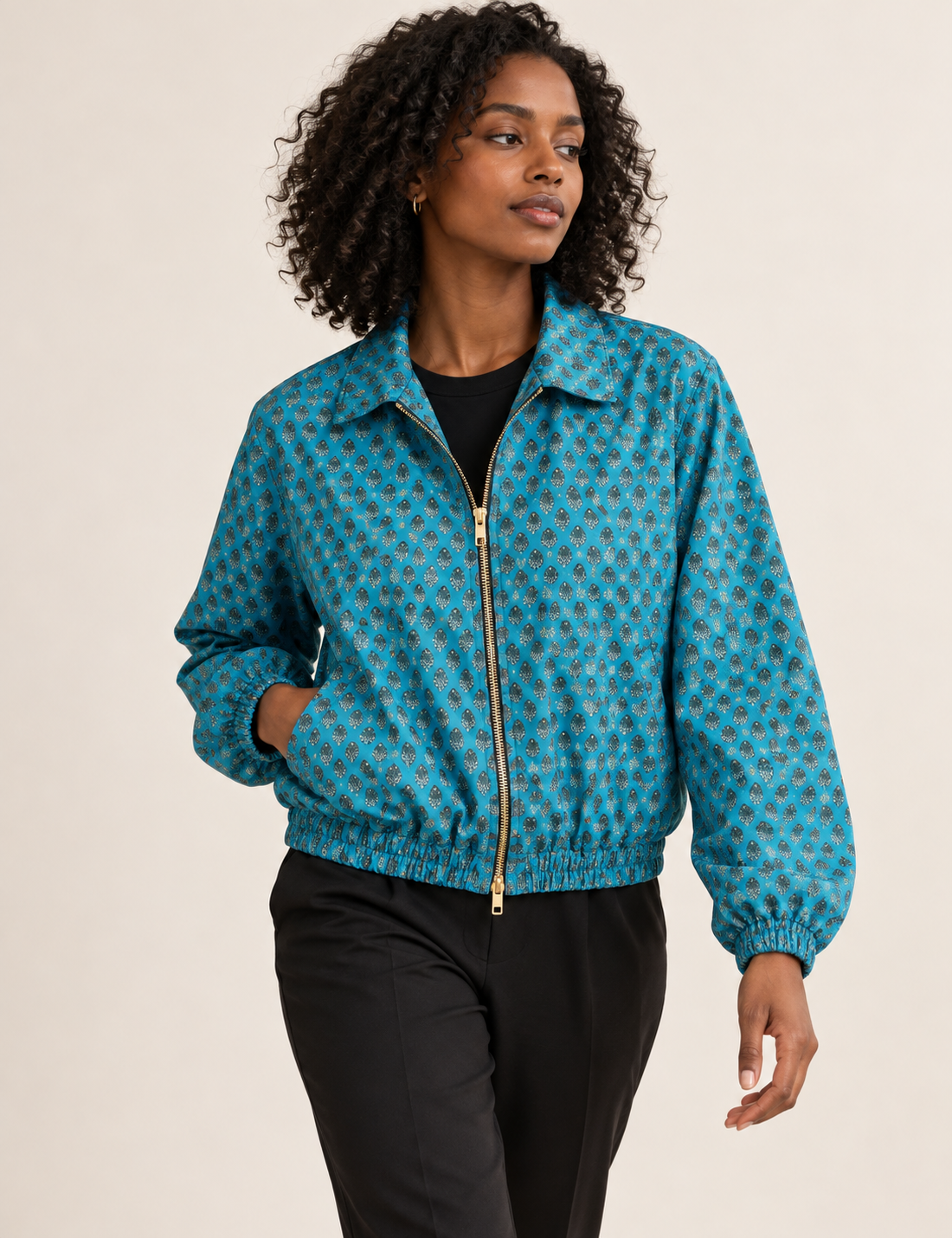 Woman wearing a yellow floral bomber jacket with front zipper, elastic cuffs, and side pockets, shown from front view