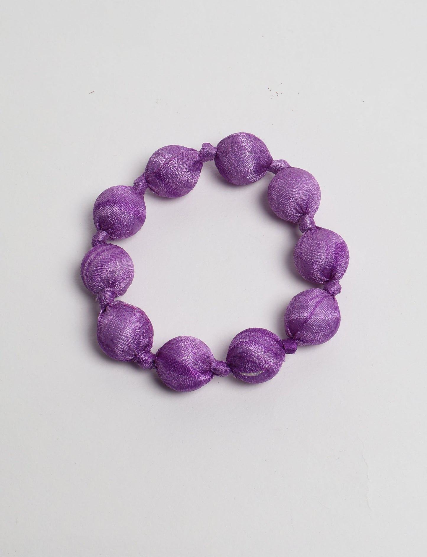 Eco friendly beaded knotted bracelet crafted from upcycled women’s clothing and repurposed sari fabrics, showcasing circular fashion and sustainable apparel.