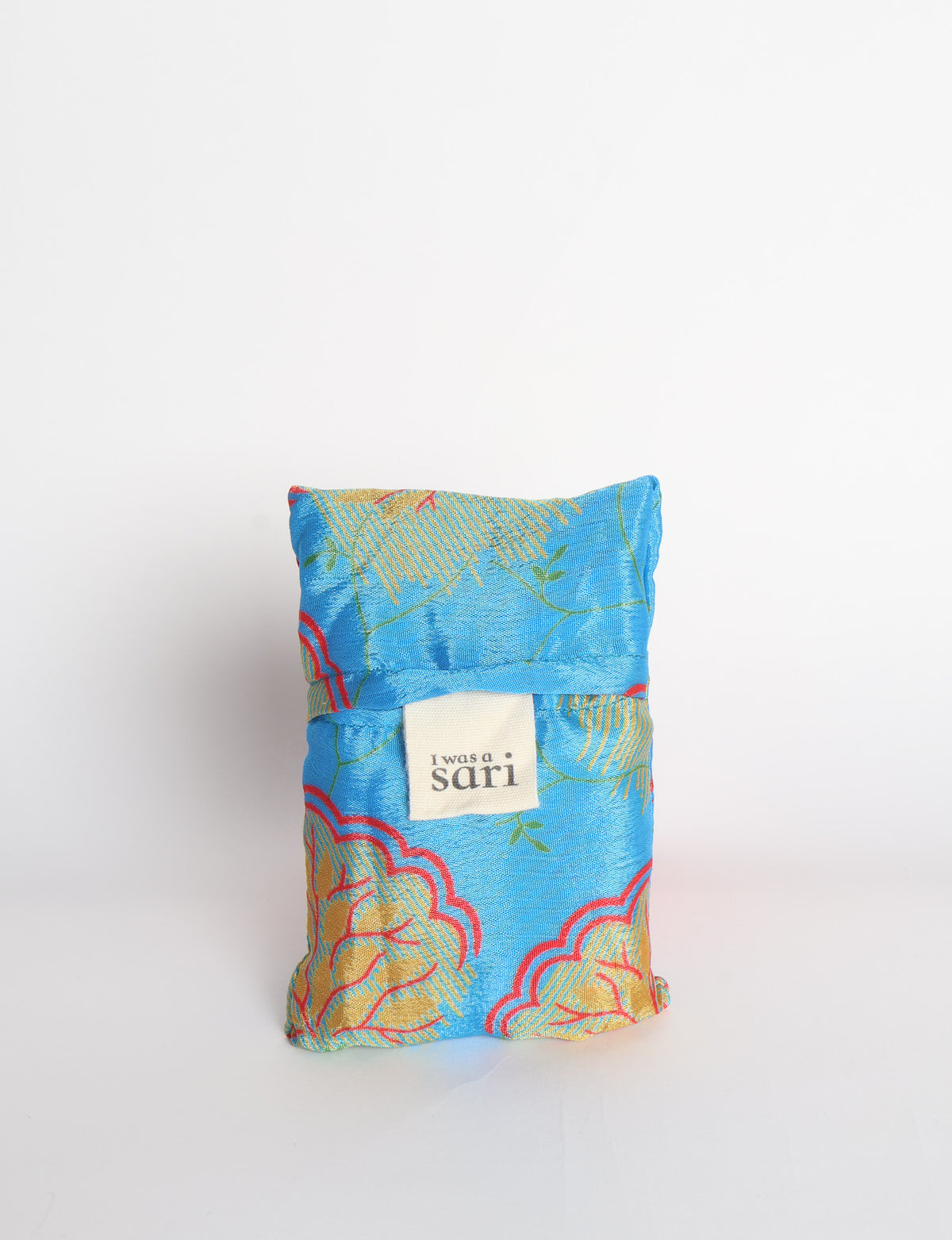 Blue reusable bag with multicolor tropical floral pattern folded with "I was a sari" label visible on front