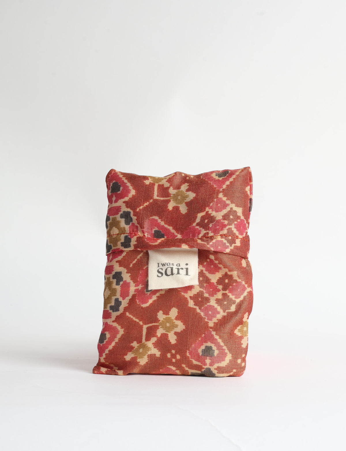 Blue reusable bag with tropical floral pattern in pink, yellow, and green, shown hanging with handles visible