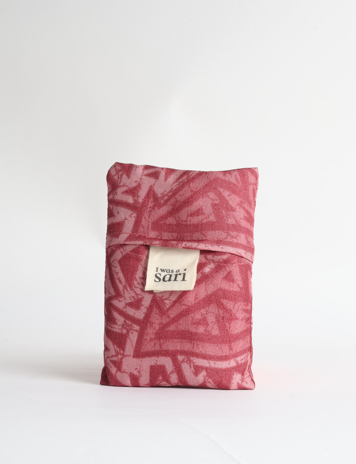 Blue reusable bag with tropical floral pattern in pink, yellow, and green, shown hanging with handles visible