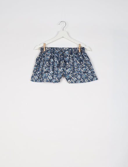 Blue tropical print shorts with elastic waistband hanging on white hanger against white background