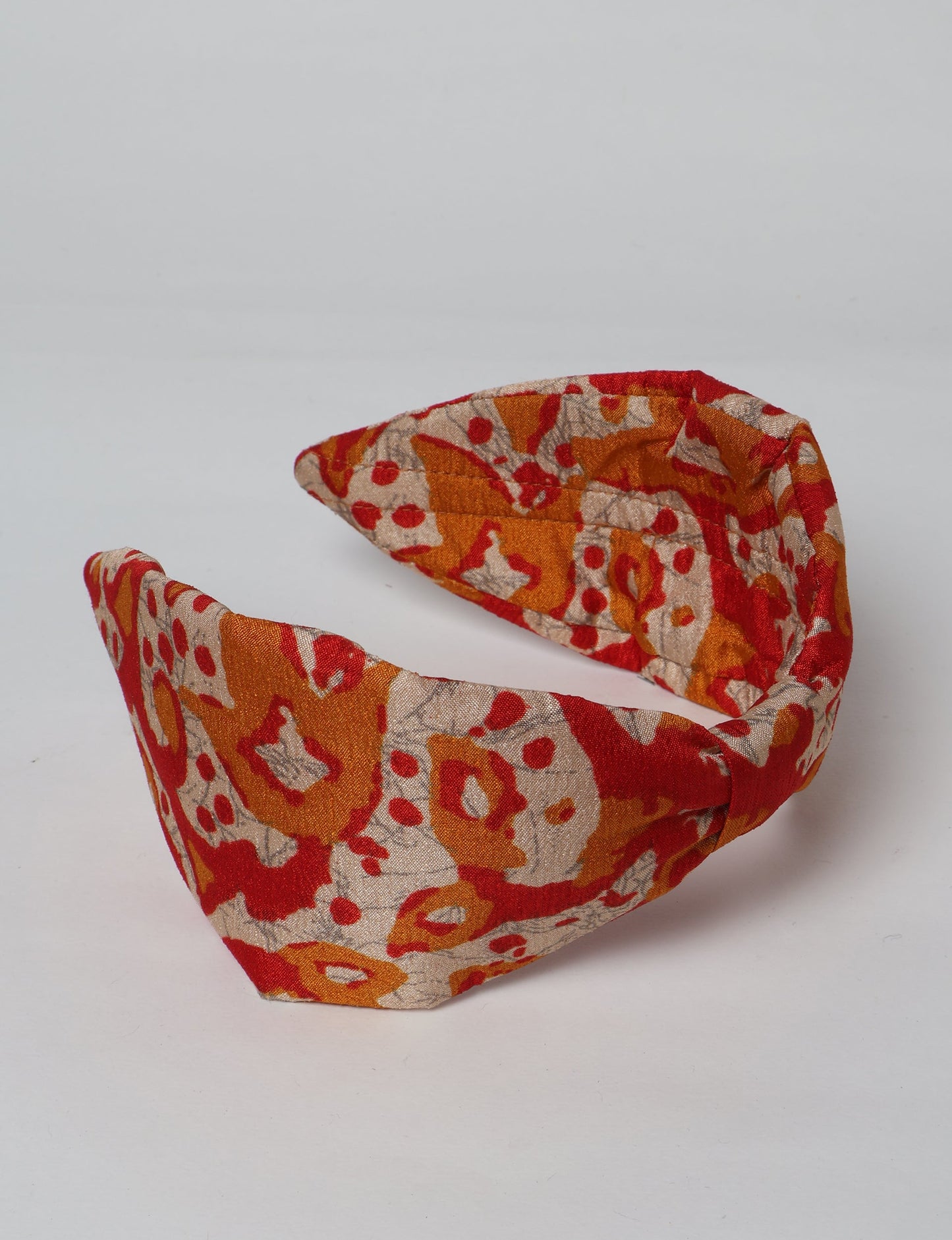 Upcycled sari hairband with central knot, handmade in India — an eco friendly fashion accessory representing green fashion, upcycled women’s clothing, fair trade fashion, and earth friendly clothing made from recycled sari textiles.