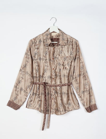 Beige floral long-sleeve shirt with button front, chest pocket, patterned cuffs, and matching fabric belt on hanger