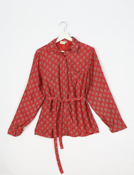 Red long-sleeve button-up shirt with beige leaf pattern, collar, chest pocket, and waist tie, hanging on white hanger