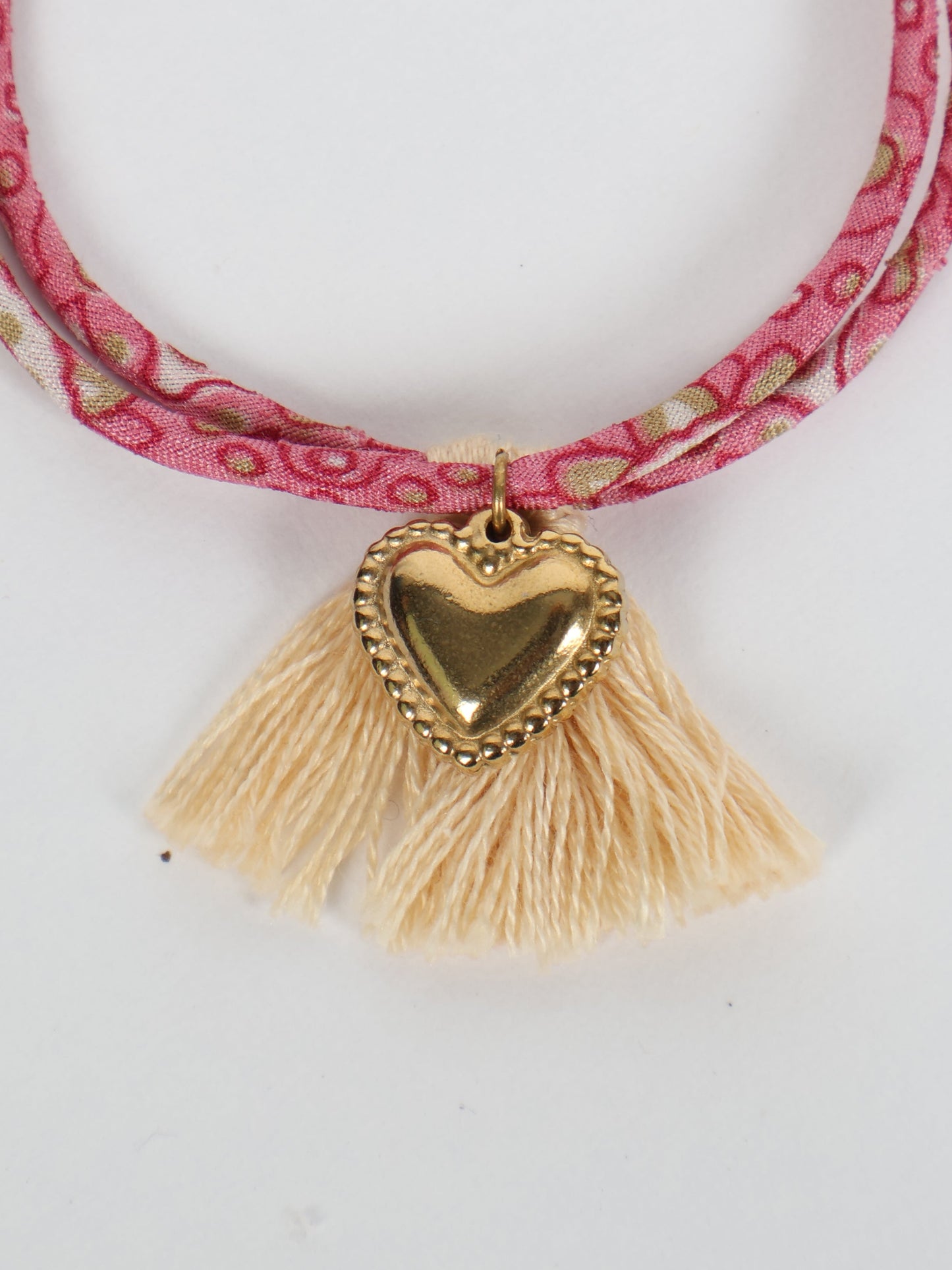 Handmade rope bracelet from recycled sari fabric with gold heart charm and tassels—eco friendly cloth, climate neutral fashion, and upcycled women’s clothing.
