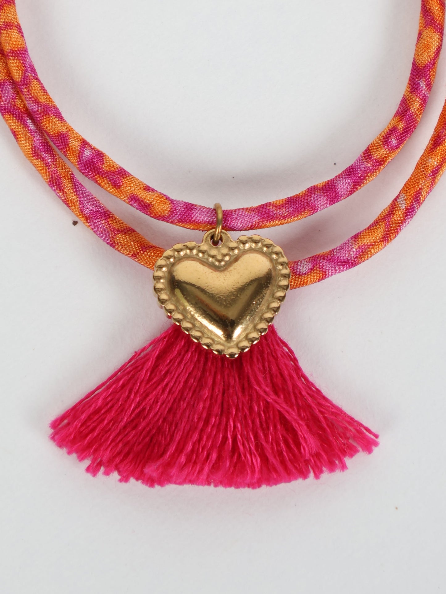 Handmade rope bracelet from recycled sari fabric with gold heart charm and tassels—eco friendly cloth, climate neutral fashion, and upcycled women’s clothing.