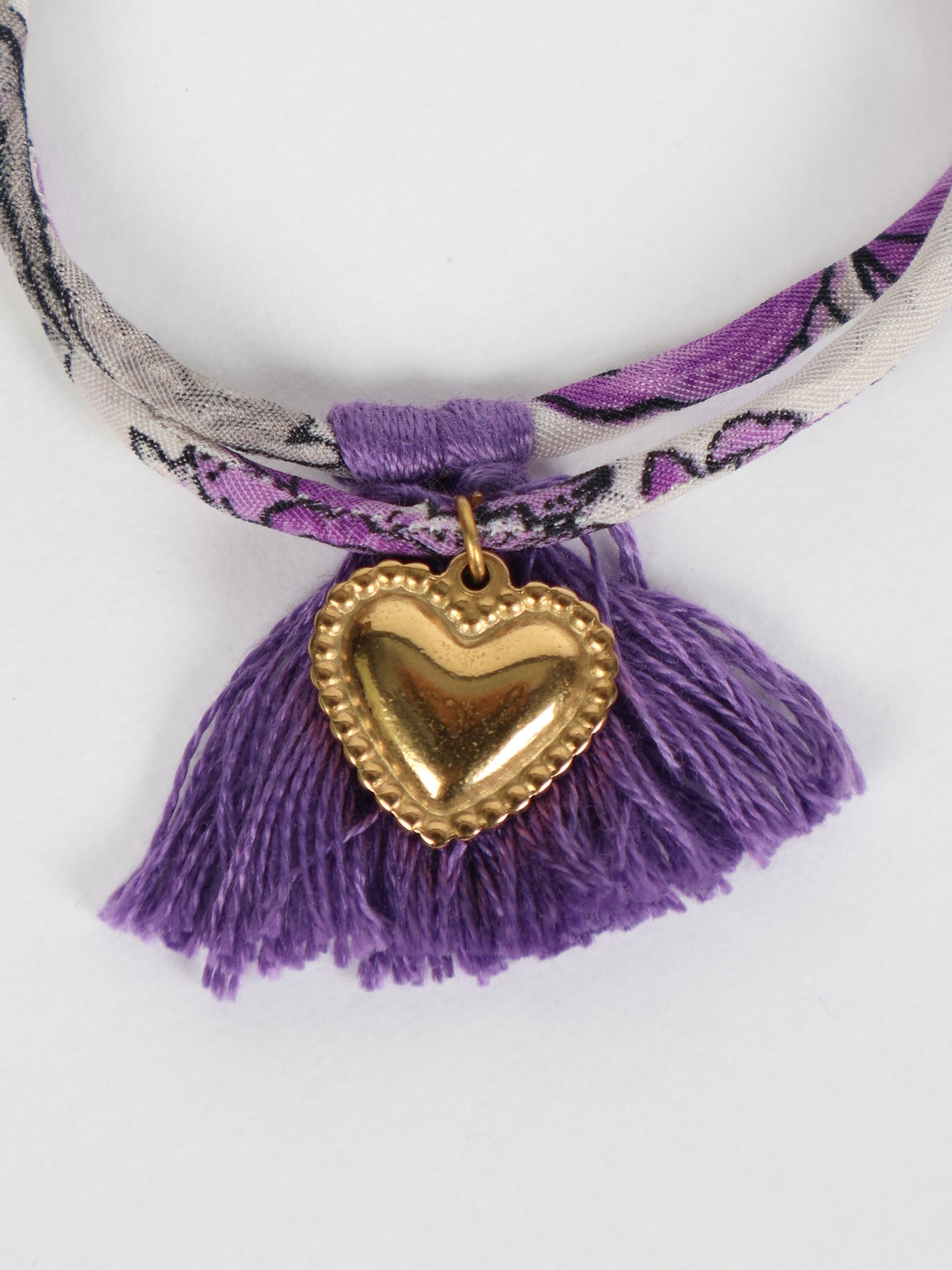 Handmade rope bracelet from recycled sari fabric with gold heart charm and tassels—eco friendly cloth, climate neutral fashion, and upcycled women’s clothing.