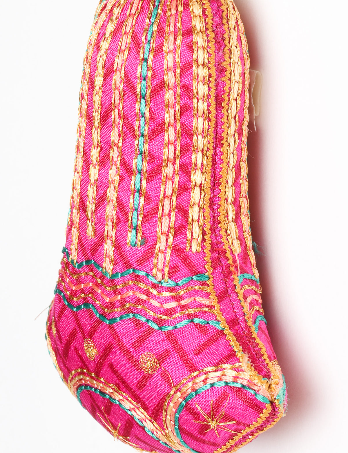 Close-up of a pink fabric bell ornament with gold, teal, and peach embroidered vertical stripes and floral patterns