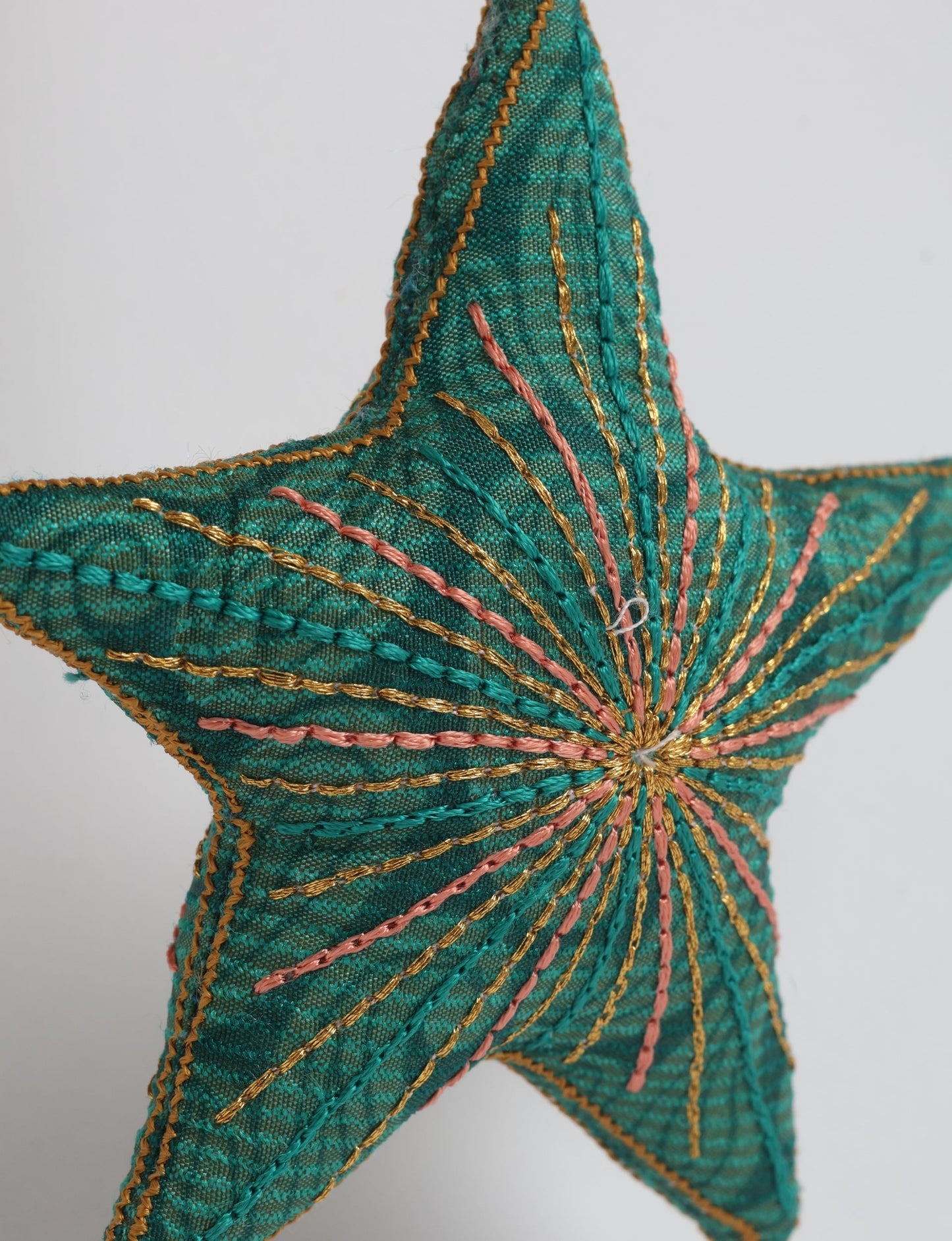 Timeless star ornament made from recycled sari fabric, featuring silk and metallic embroidery, crafted as part of green fashion, recycled clothing design, environmentally friendly clothing practices, and repurposed clothing traditions.
