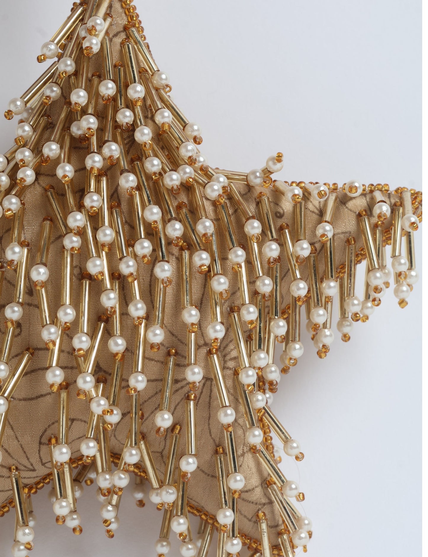 Gold colored star ornament made from ivory and gold preloved saris, filled with organic cotton and decorated with silver hand embroidery, representing upcycled clothing, green fashion, fair trade fashion, recycled material clothing, repurposed clothing, climate neutral clothing, eco clothing, second hand clothing, recycled sustainable fashion, and sustainable women’s clothing.