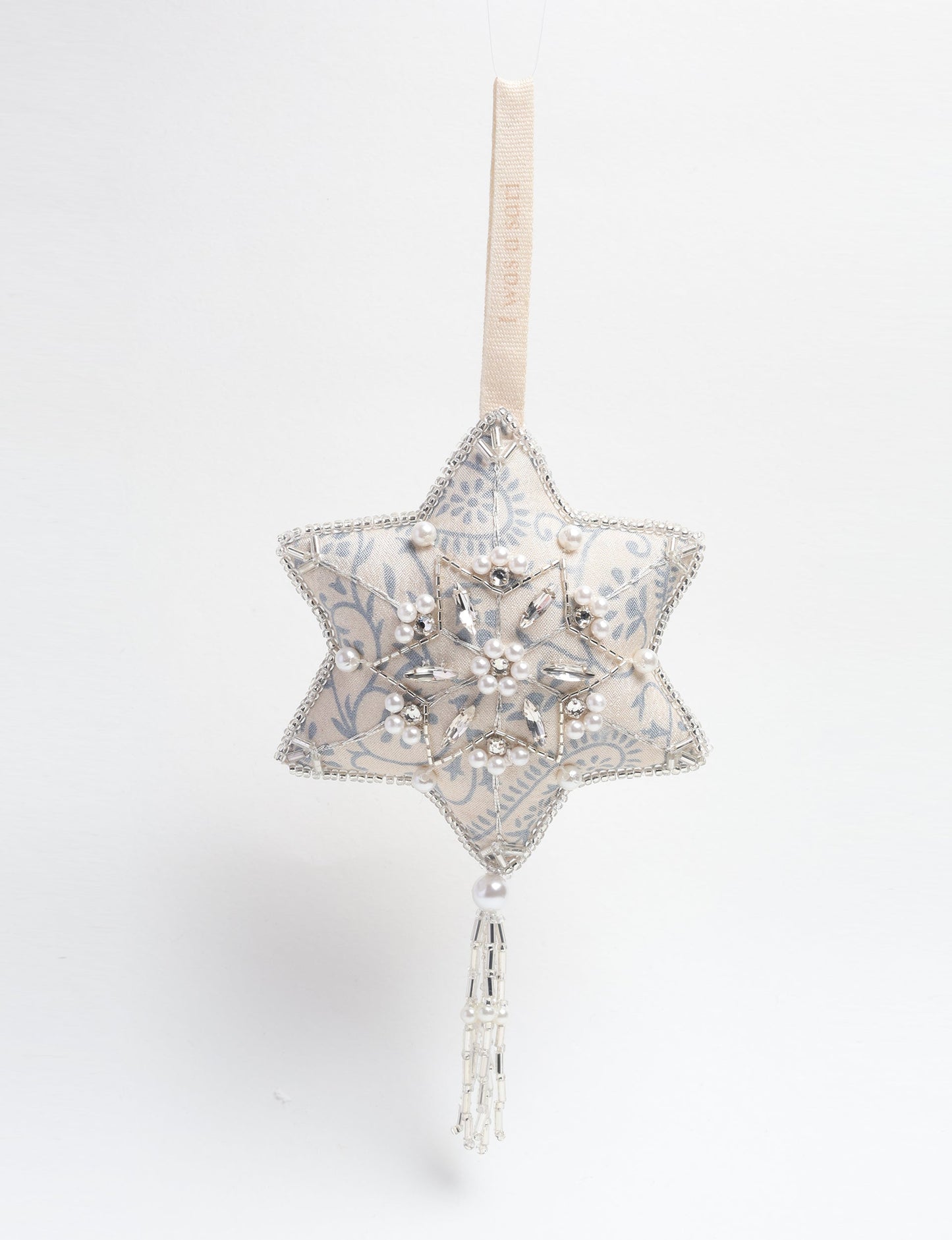 Silver snowflake ornament made from ivory and grey recycled sari products, enhanced with silver beads and pearls. Designed for lovers of eco friendly products, climate neutral clothing, and repurposed clothing, supporting zero waste clothing and conscious clothing movements.