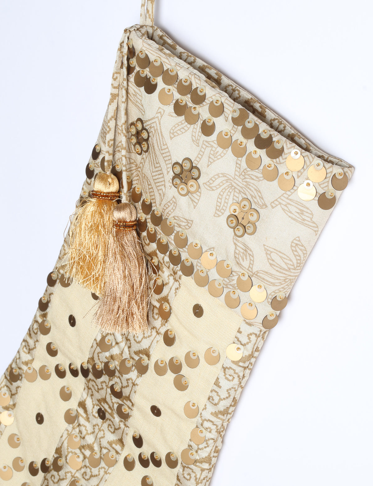 Christmas stocking with beige and brown floral and stripe pattern, gold sequins, and two beige tassels on hanging loop