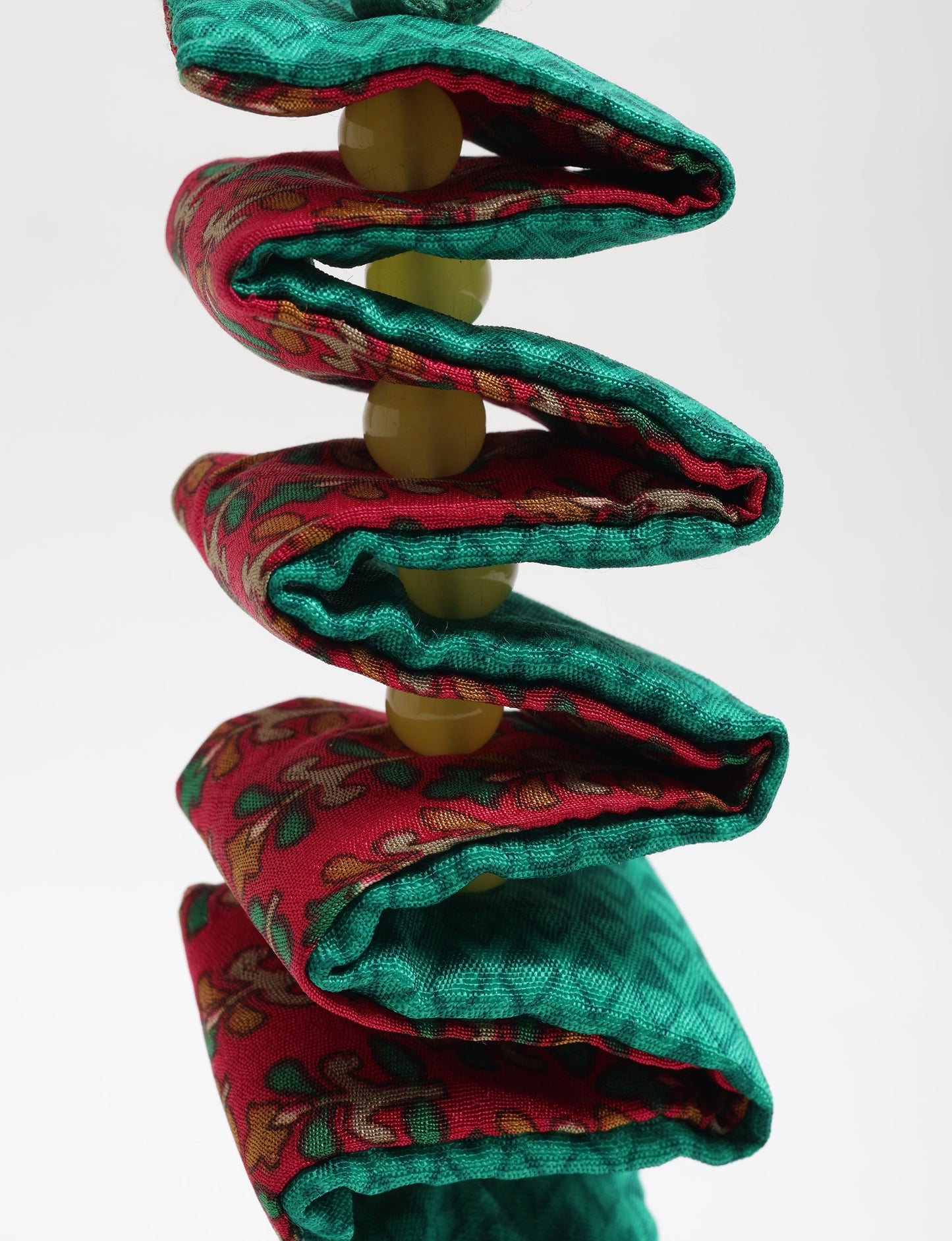 Handcrafted upcycled candy cane ornament made from recycled sari fabric and organic cotton, reflecting fair trade fashion and circular fashion principles in eco friendly, repurposed clothing craftsmanship.