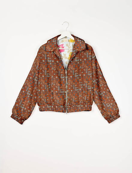 Orange bomber jacket with Indian ethnic geometric pattern, front zipper, collar, and elastic cuffs, shown on hanger front