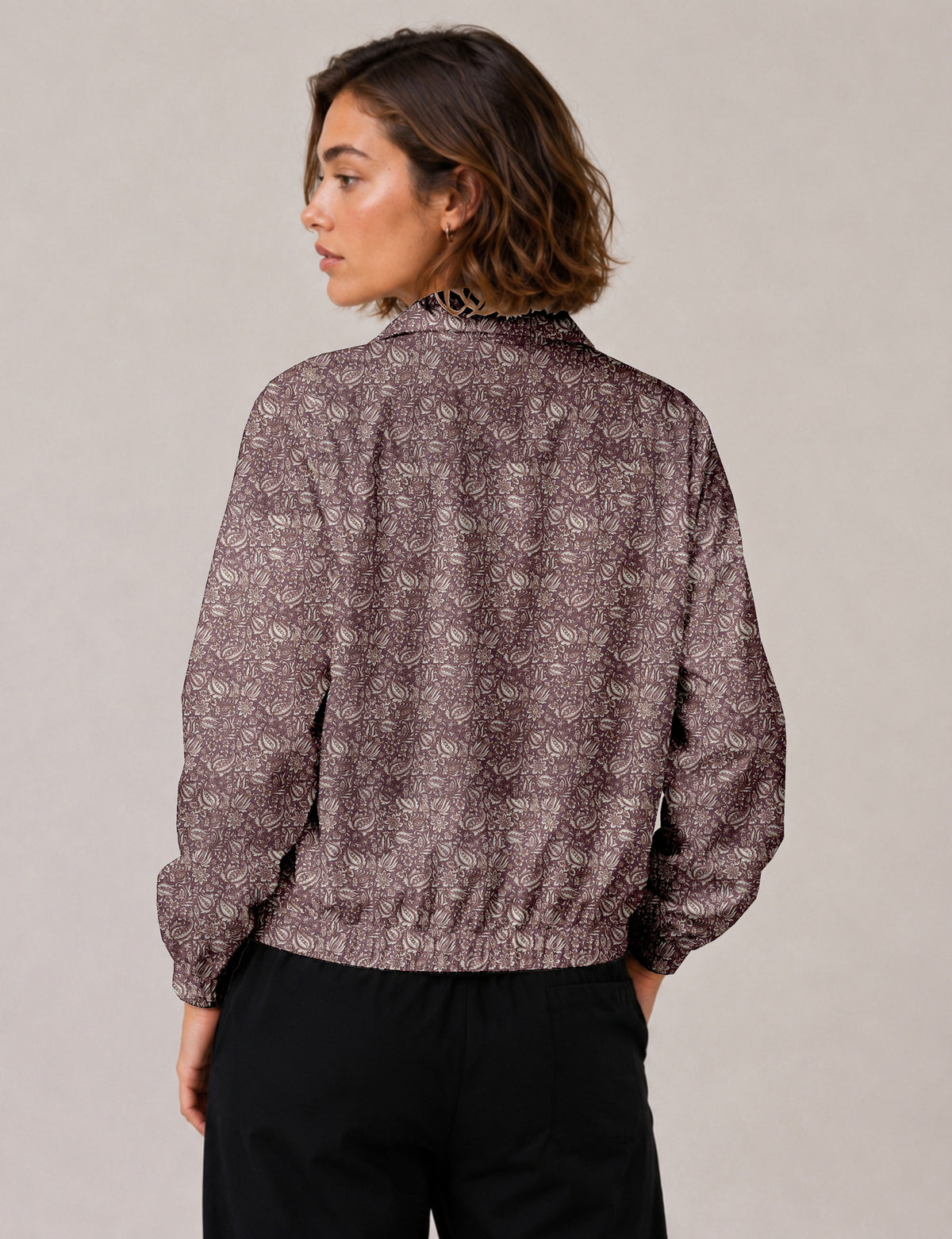 Woman wearing a yellow floral bomber jacket with front zipper, elastic cuffs, and side pockets, shown from front view