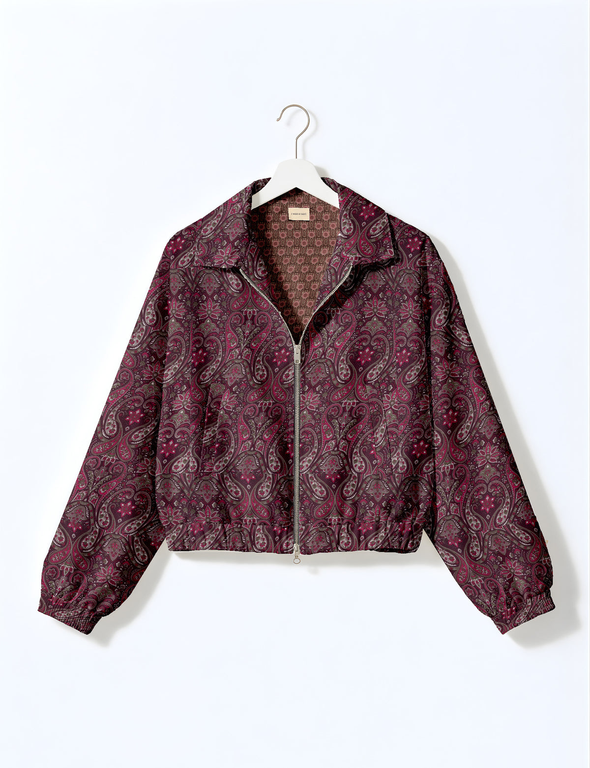 Brown floral bomber jacket with front zipper, elastic cuffs and hem, hanging on white hanger, red floral inner lining visible