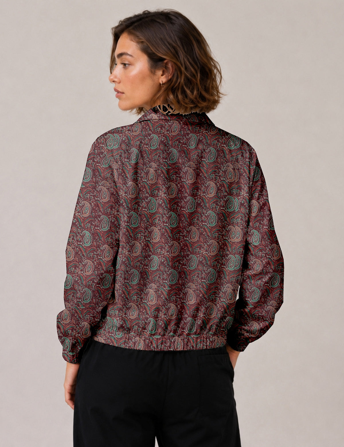 Woman wearing a yellow floral bomber jacket with front zipper, elastic cuffs, and side pockets, shown from front view