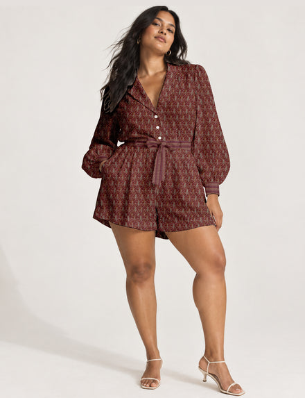 Women’s long sleeve playsuit with wrap-style front, V neckline, notched collar, adjustable waist tie and mid-thigh shorts.
