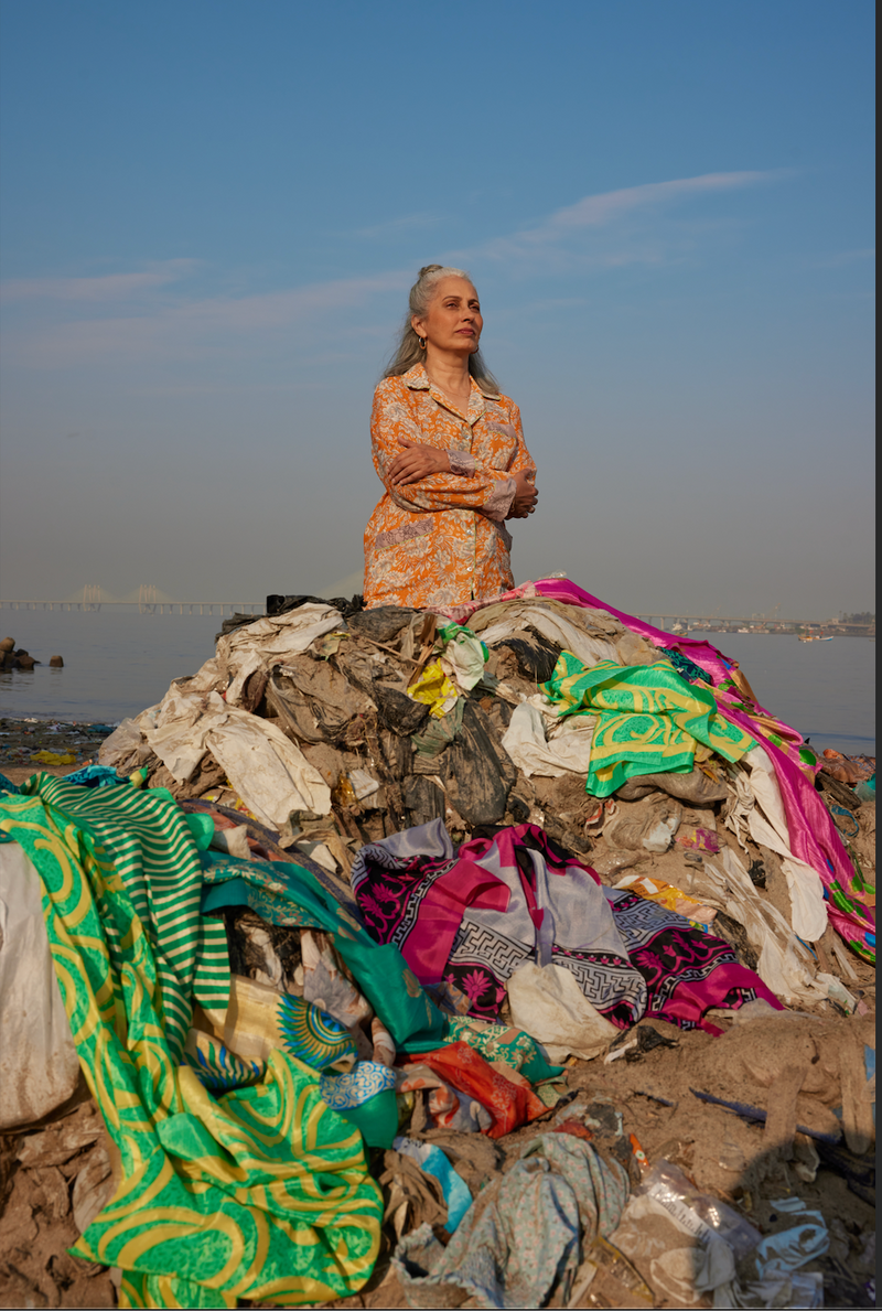 woman wearing I was a Sari clothing standing near a big pile of textile waste