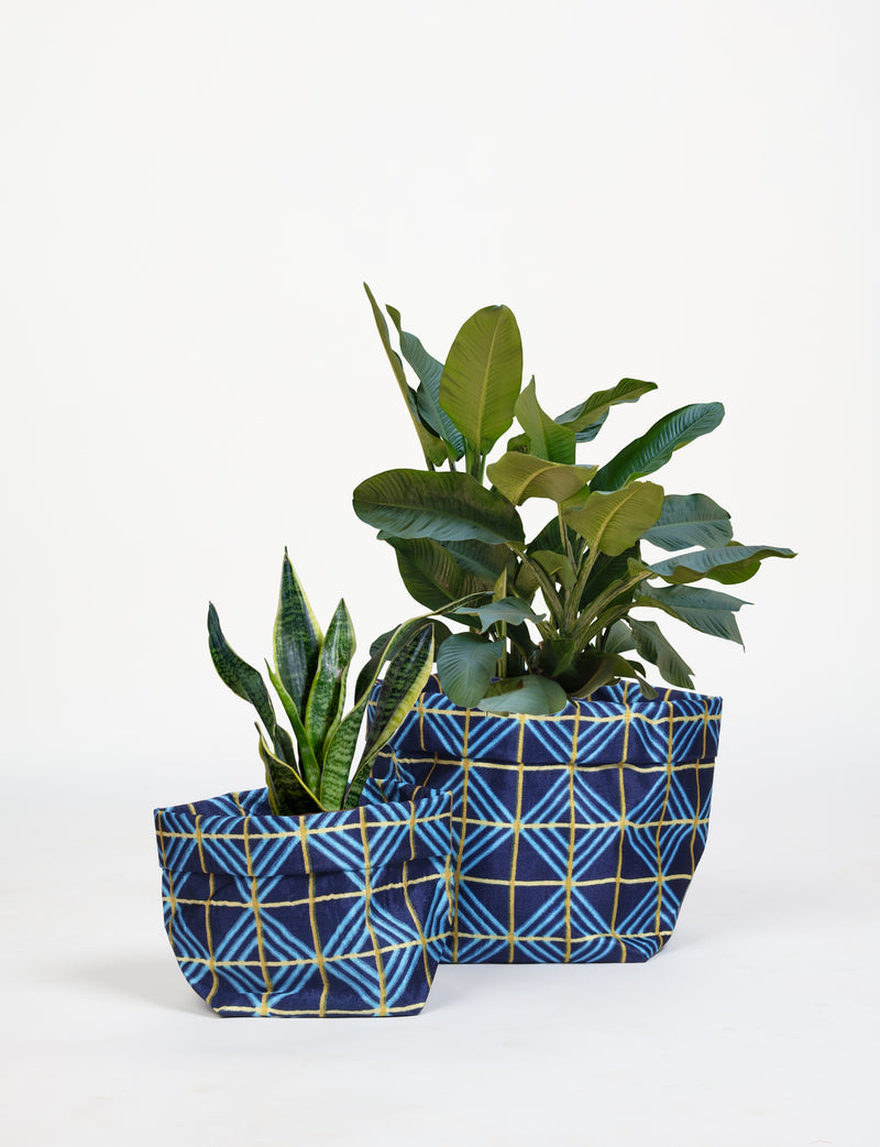 Set of two blue geometric patterned fabric plant pot covers in small and medium sizes, shown with green plants inside