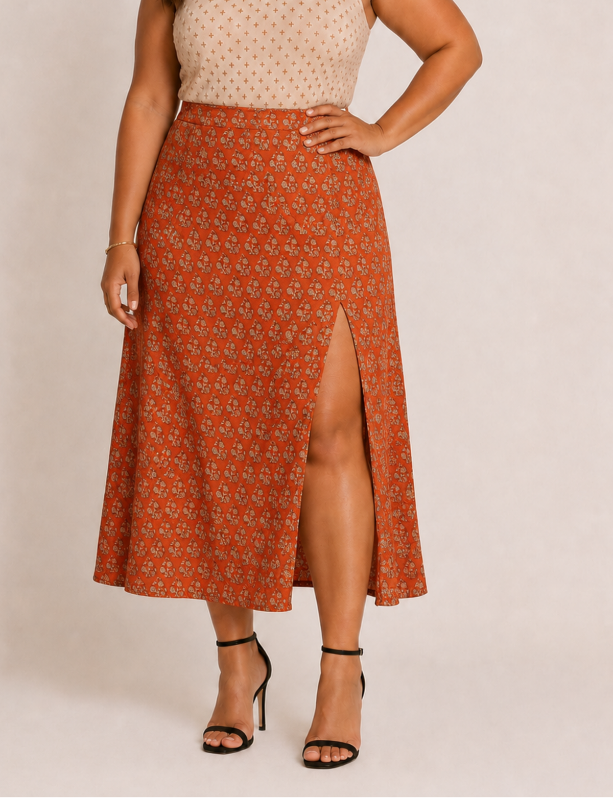 Woman wearing an orange A-line skirt with a tropical pattern and front slit, paired with black ankle-strap heels