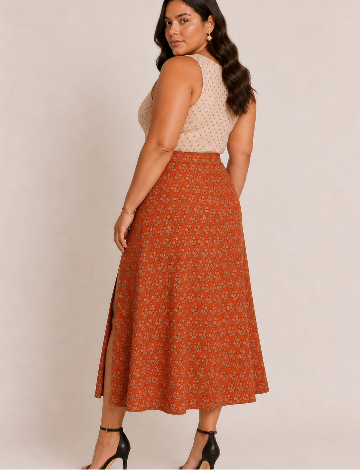 Woman wearing an orange A-line skirt with a tropical print and side slit, paired with a beige sleeveless top