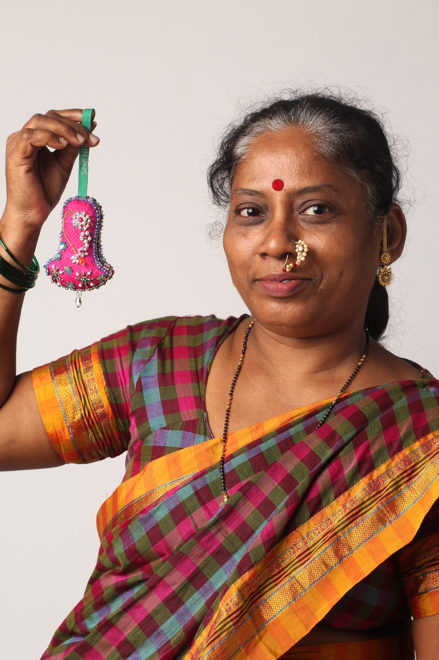 Bell-shaped Artisans Christmas Ornament embroidered with a nosering design, made from upcycled saris. A sustainable, eco-friendly holiday décor piece that supports ethical, slow fashion and recycled sari products.