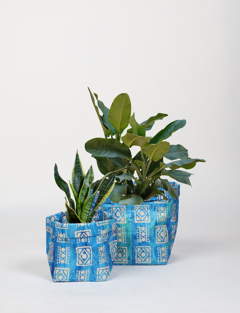 Set of two blue geometric patterned fabric plant pot covers, sizes small and medium, shown with green plants inside