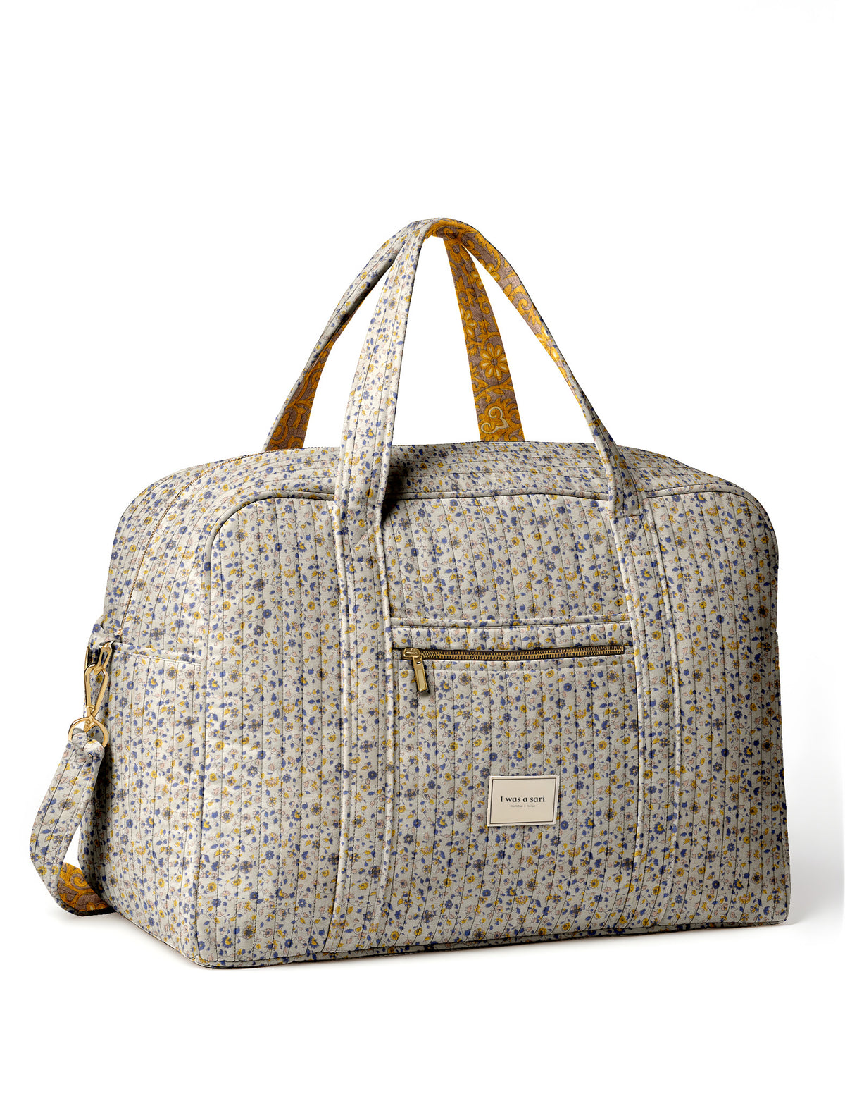 Brown quilted duffle bag with paisley pattern, front zip pocket, dual handles, and label reading "I was a sari"