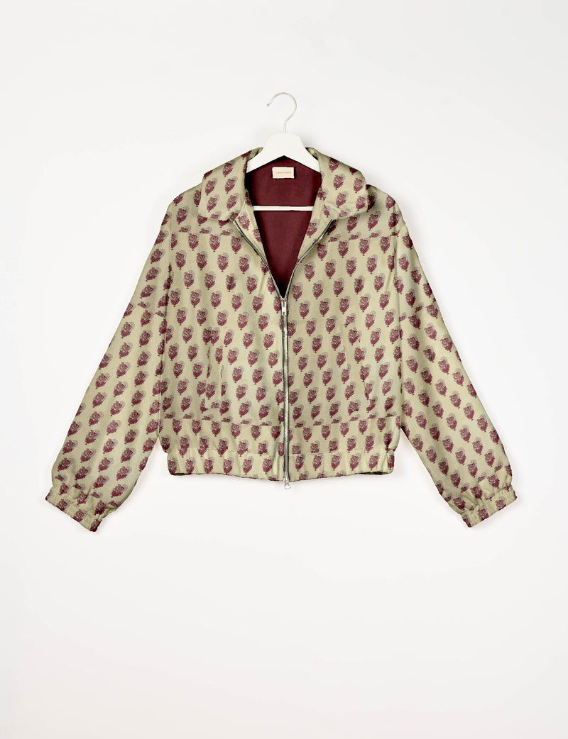 Beige bomber jacket with maroon leaf pattern, front zipper, elastic cuffs, and collar, shown hanging on white hanger