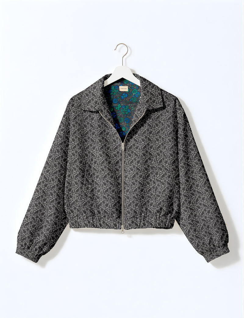 Brown floral bomber jacket with front zipper, elastic cuffs and hem, hanging on white hanger, red floral inner lining visible