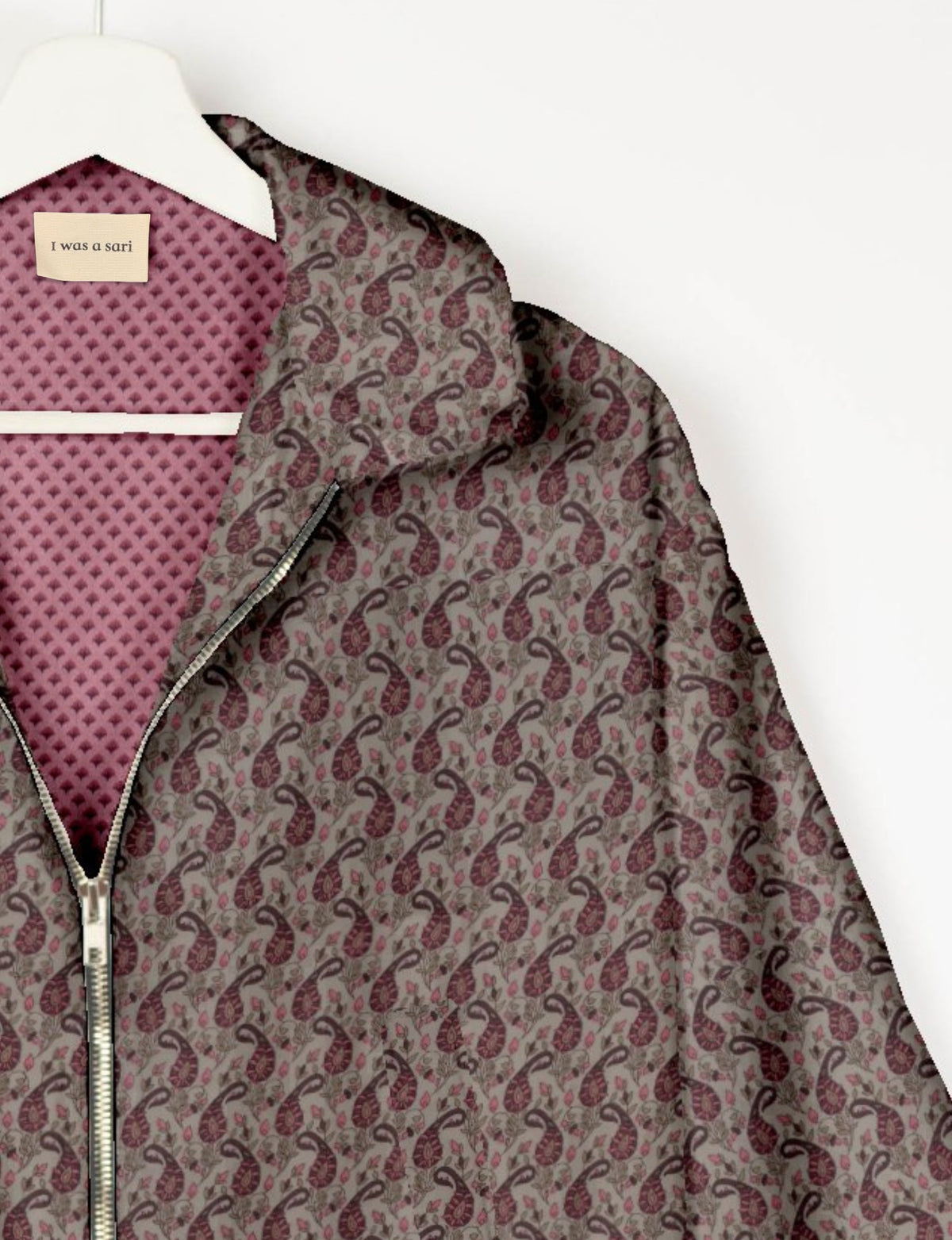 Beige bomber jacket with maroon paisley pattern, silver zipper, and pink patterned lining with label "I was a sari" visible