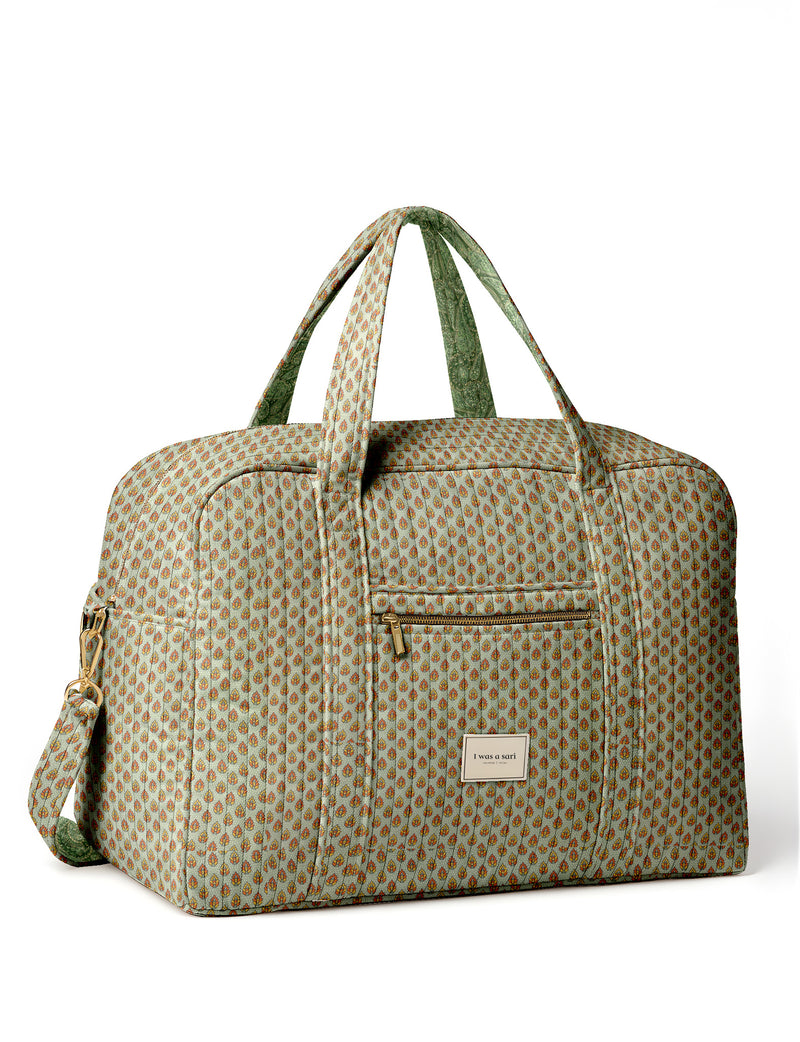 Brown quilted duffle bag with paisley pattern, front zip pocket, dual handles, and label reading "I was a sari"