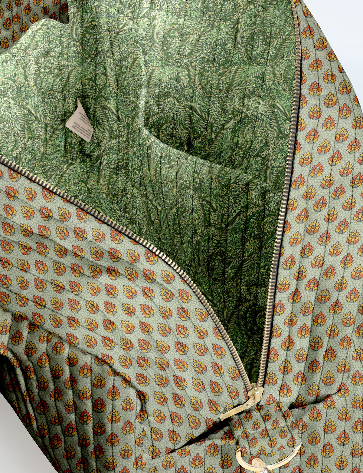 Brown quilted duffle bag with paisley pattern, front zip pocket, dual handles, and label reading "I was a sari"