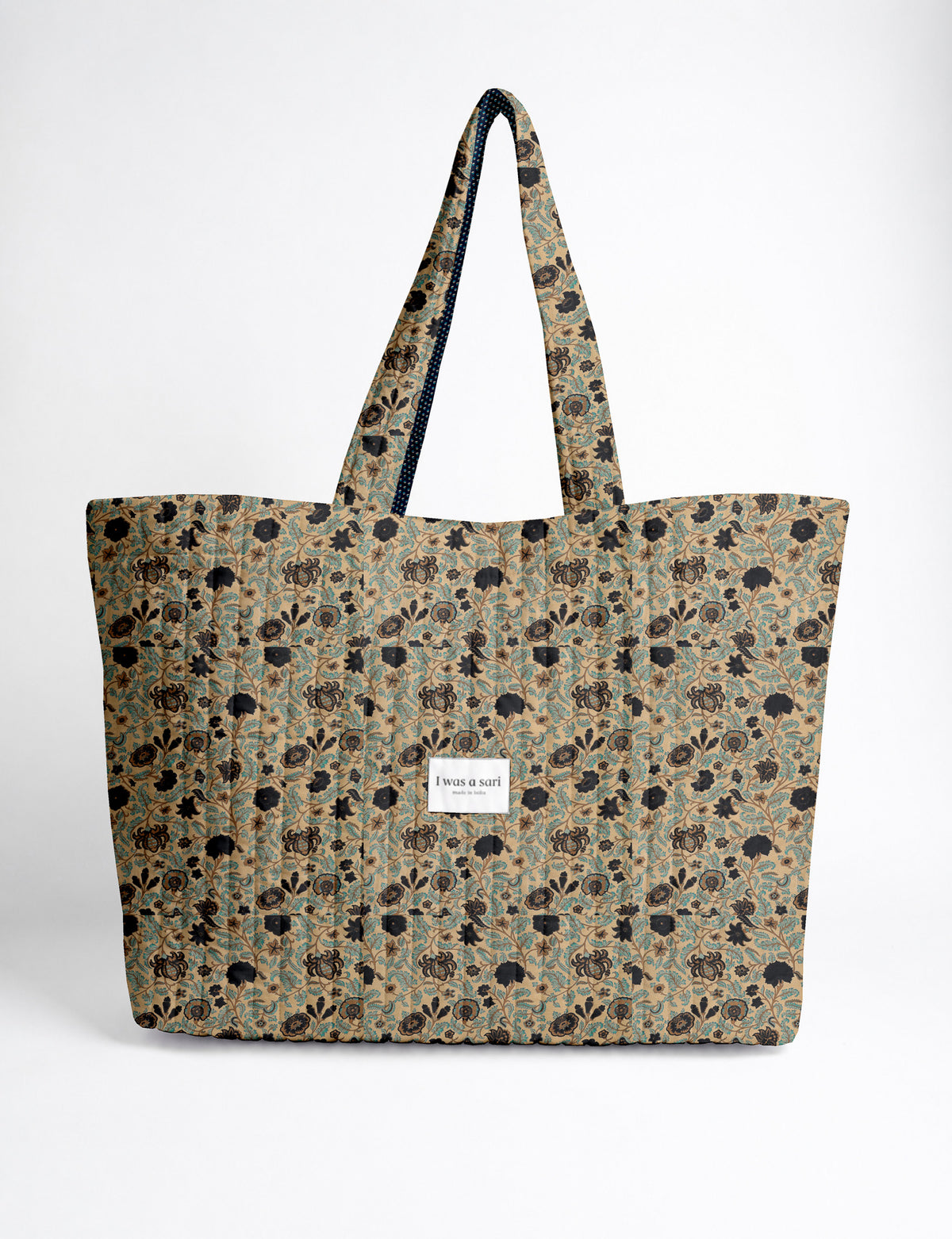 Quilted yellow tropical patterned beach bag with long handles and white label reading "I was a sari" front view