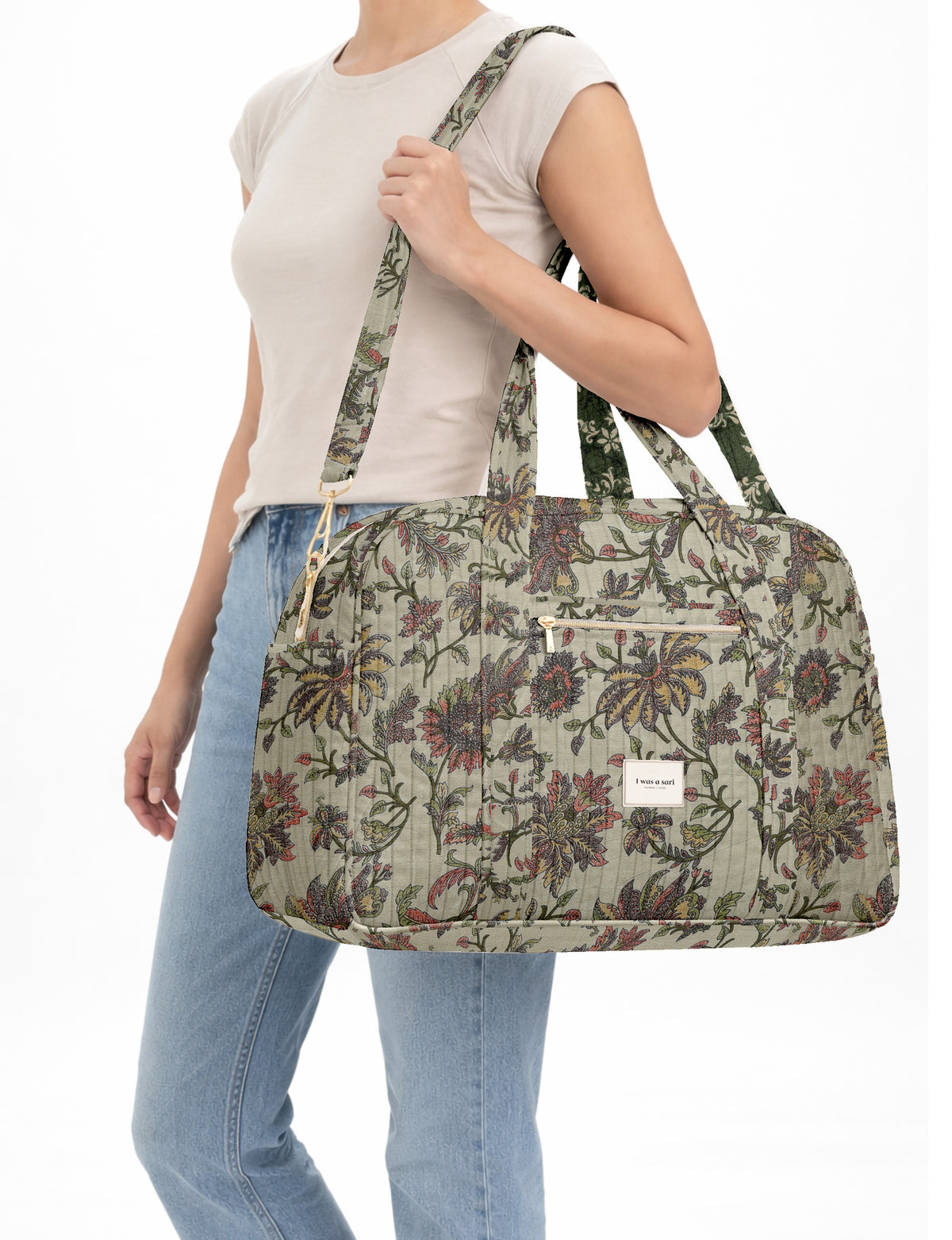 Brown quilted duffle bag with paisley pattern, front zip pocket, dual handles, and label reading "I was a sari"