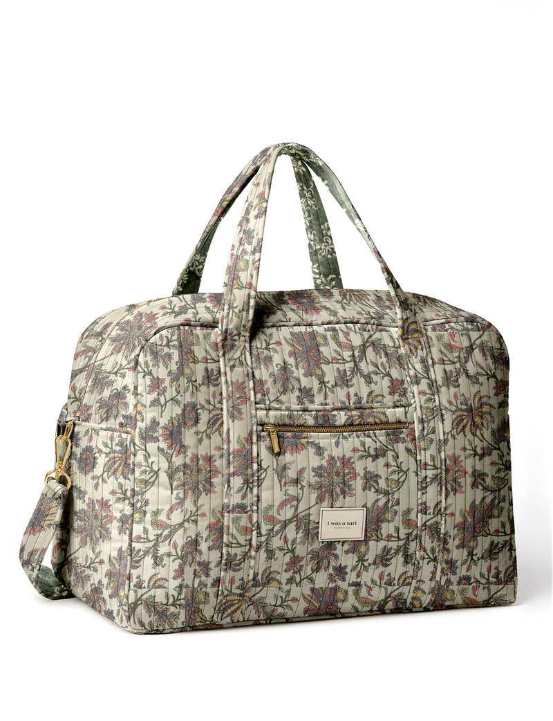 Brown quilted duffle bag with paisley pattern, front zip pocket, dual handles, and label reading "I was a sari"