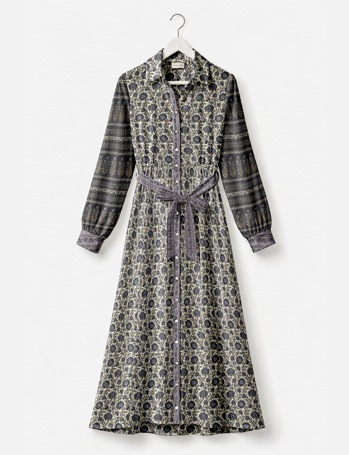 Long shirt dress with beige and dark blue floral and stripe patterns, button front, long sleeves, and waist tie, hanging on