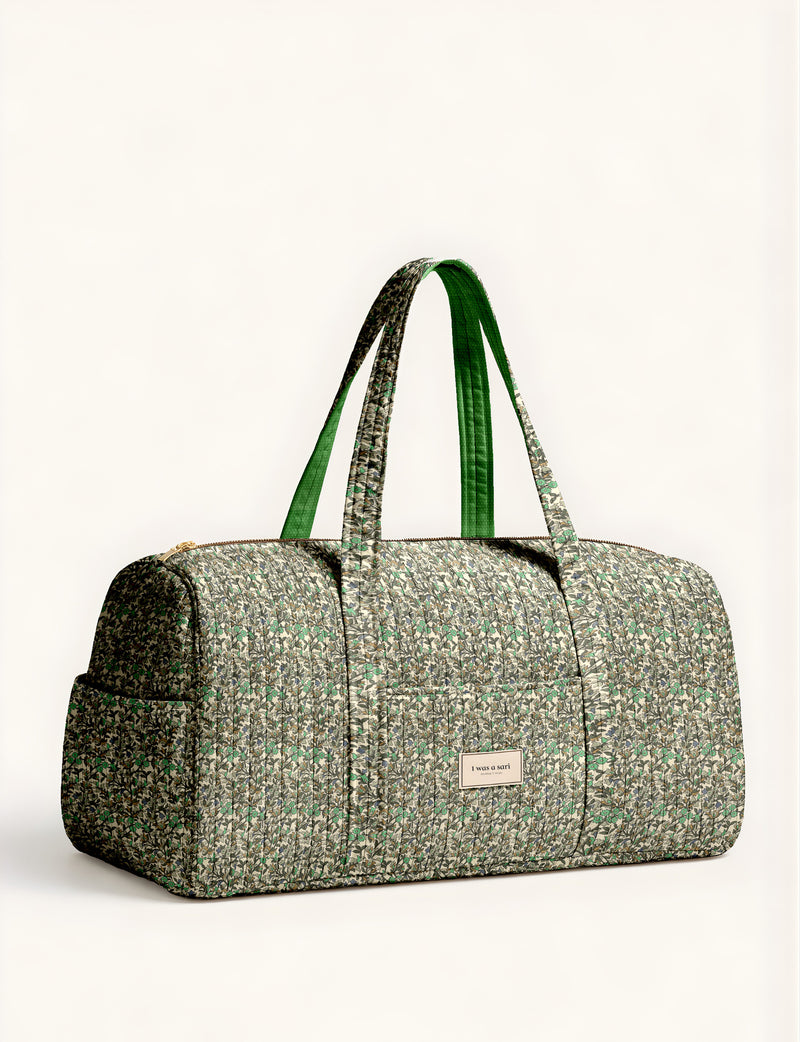 Quilted brown paisley barrel bag with double handles, front pocket, and gold zipper, shown in side angle view