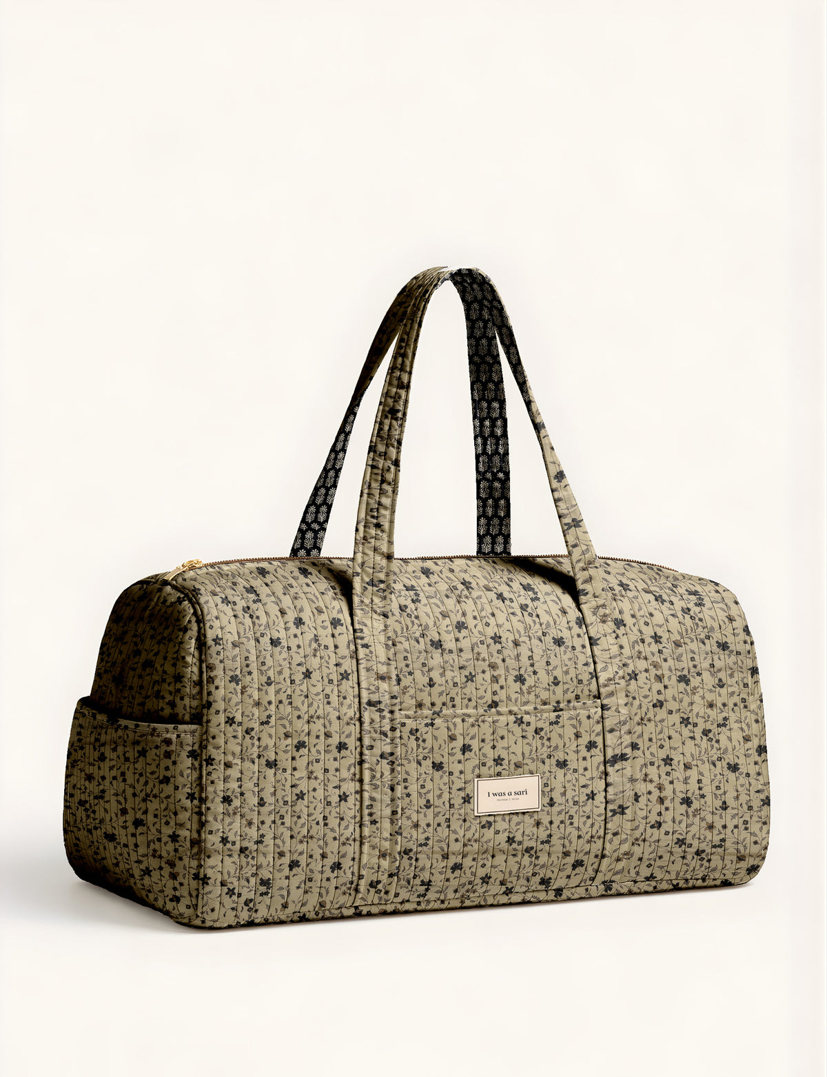 Quilted brown paisley barrel bag with double handles, front pocket, and gold zipper, shown in side angle view