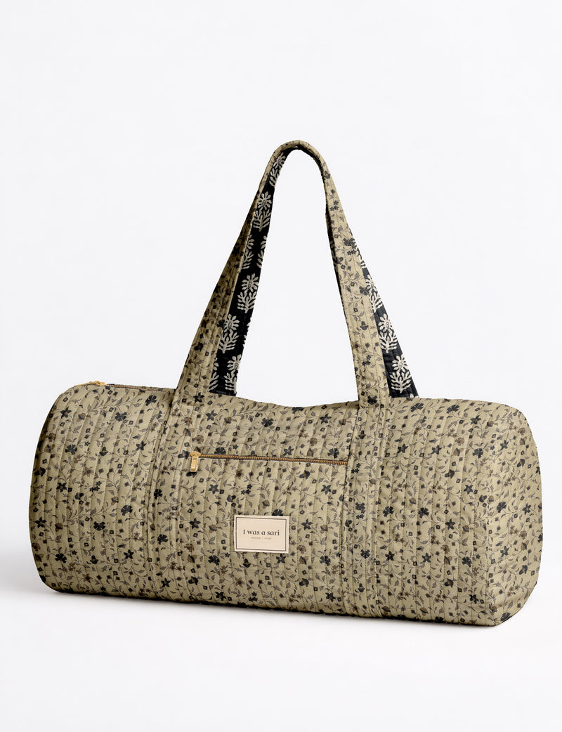 Brown paisley quilted bowling bag with front zipper pocket, held by person wearing white shirt and light blue jeans