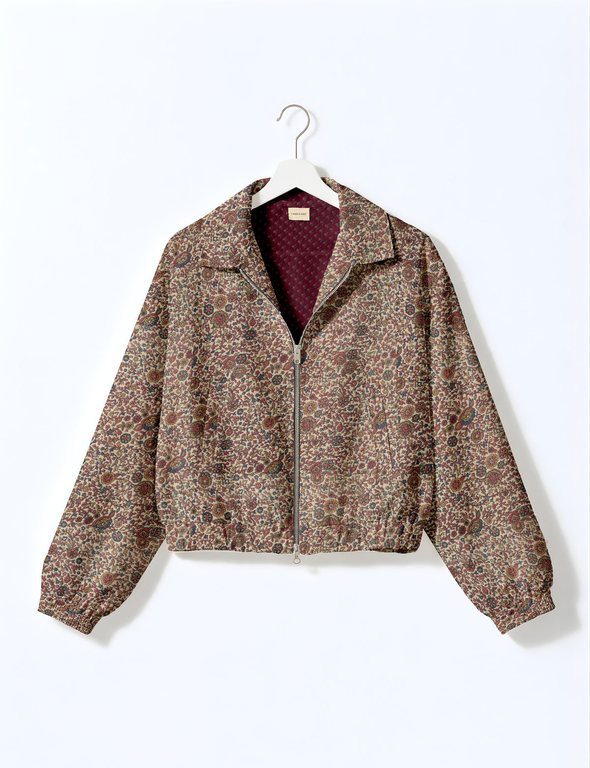 Brown floral bomber jacket with front zipper, elastic cuffs and hem, hanging on white hanger, red floral inner lining visible