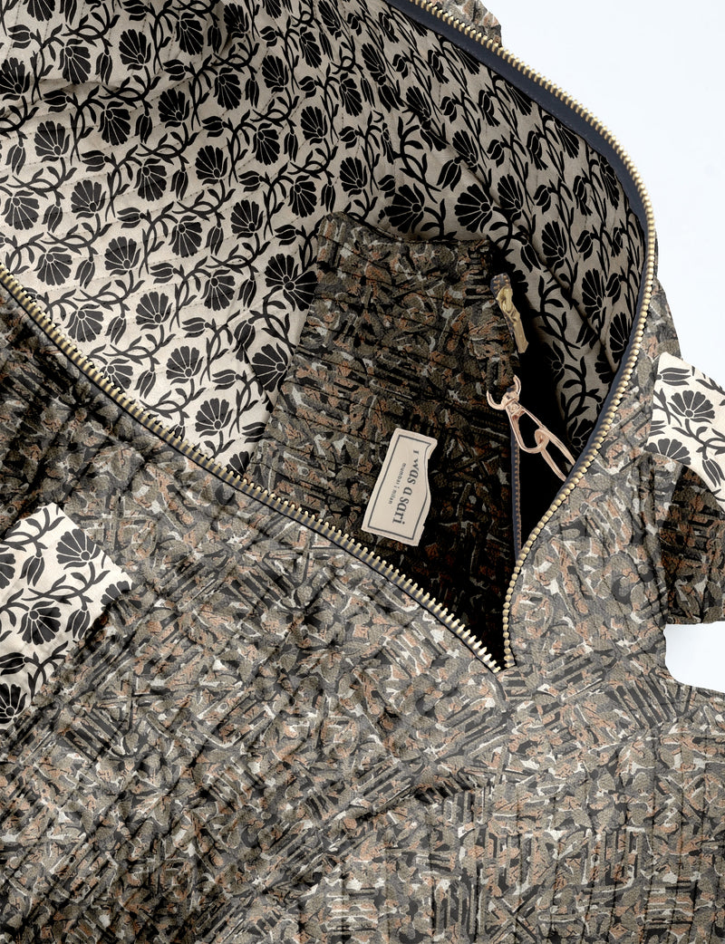 Quilted bowling bag with black, brown, and gray abstract pattern, gold zipper, and black floral interior lining