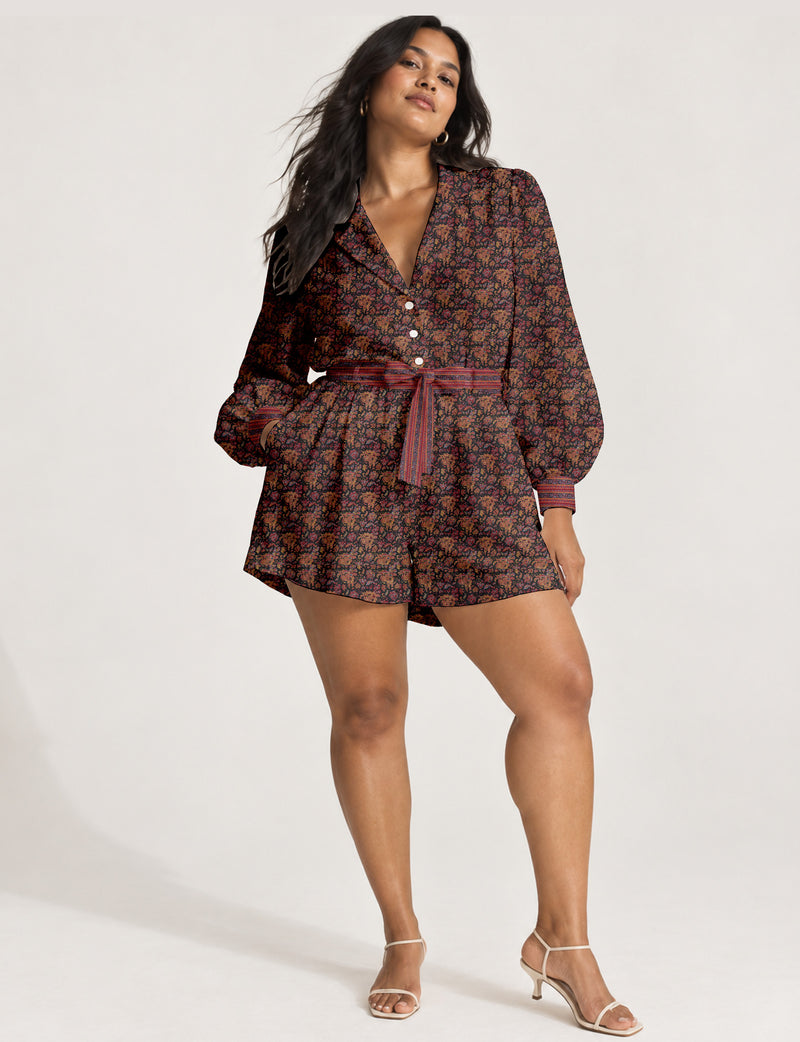 Women’s long sleeve playsuit with wrap-style front, V neckline, notched collar, adjustable waist tie and mid-thigh shorts.