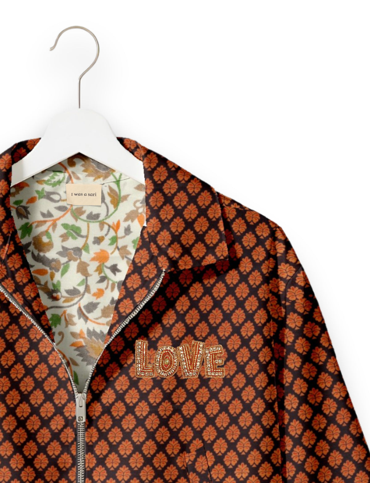 Black bomber jacket with orange leaf pattern, gold beaded "LOVE" patch, floral inner lining, and silver zipper on white