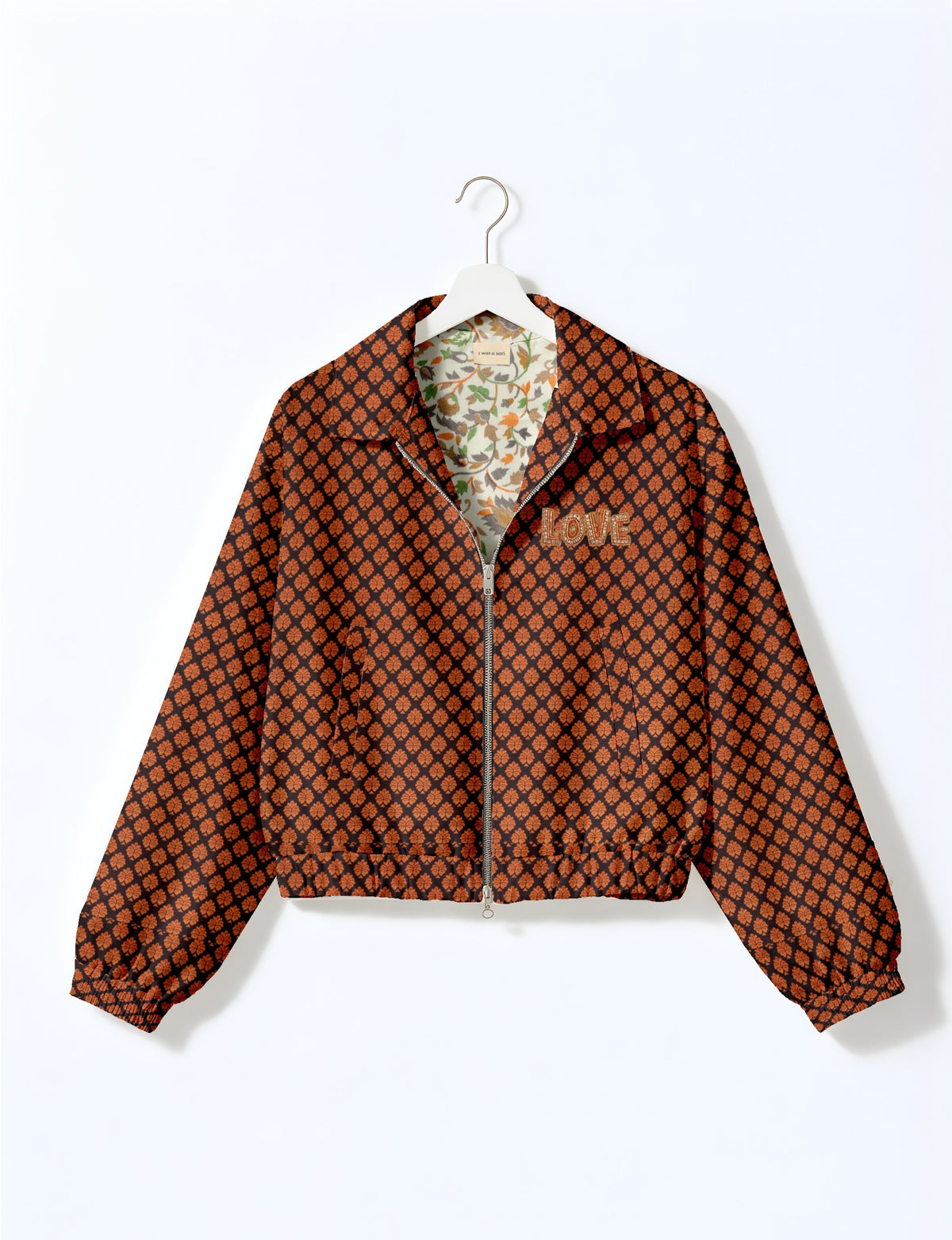 Black bomber jacket with orange leaf pattern, front zipper, elastic cuffs, and "LOVE" embroidered on chest, shown on hanger