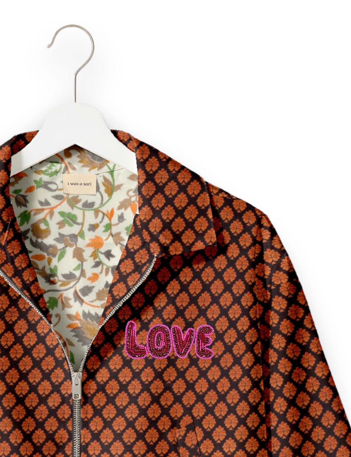 Brown bomber jacket with orange leaf pattern, pink beaded "LOVE" text on chest, floral inner lining, and silver zipper on